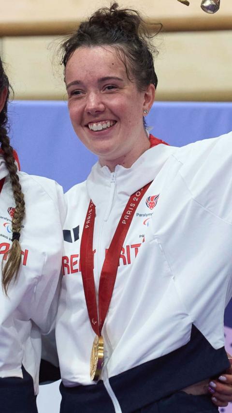Young woman with dark brown hair wearing a medal and smiling