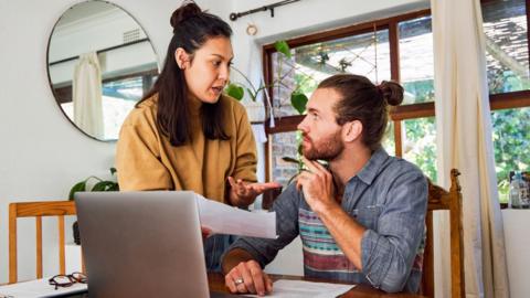 A brother and sister argue in front of an open laptop 