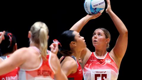 Eleanor Cardwell, wearing England's red and white netball vest top, shooting a goal in the win over Tonga at the Commonwealth Games