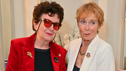 Wiltshire actress Fidelis Morgan wearing a black t-shirt, red velvet blazer and red glasses standing beside actress Celia Imrie who is wearing a white blazer.