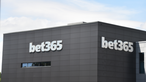 A large dark grey, block-shaped building with the words bet 365 in white lettering on the side.