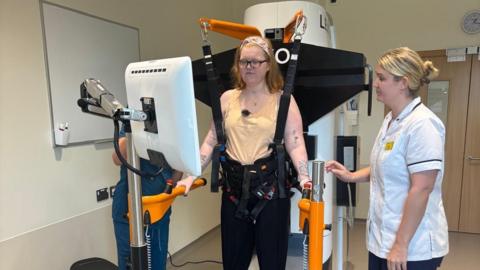 Nic Marsden, 29, using robotic technology, at the National Rehabilitation Centre at Stanford Hall in Nottinghamshire, to help her learn to walk again. A specialist stands by the side of the equipment.