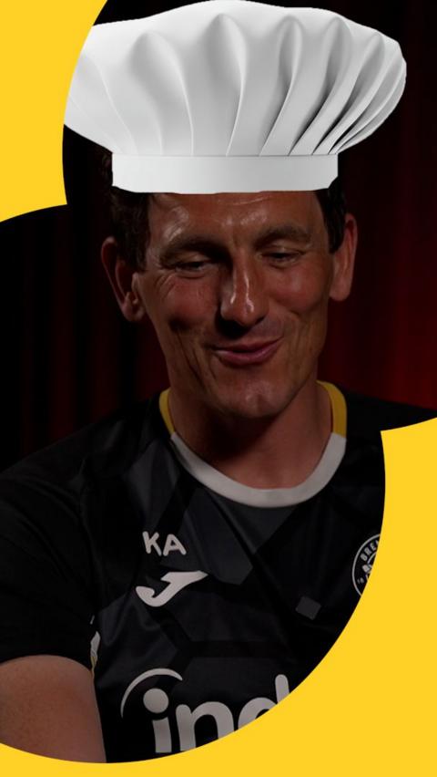 Keith Andrews smiling with a cut out of a chef's hat on his head