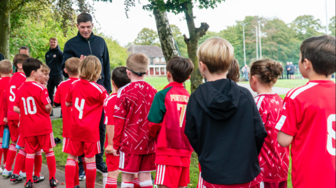 Steven Gerrard smiles as he high fives kids wearing red football tops