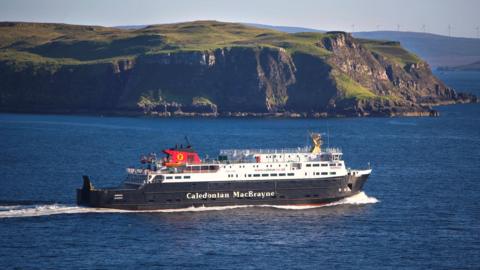 MV Hebrides is a large black and white ship with the words "Caledonian MacBrayne" in white letters along its hull. The ferry is sailing past a headland.