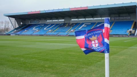 A general view of Brunton Park. A corner flag with the Carlisle United crest on it can be seen with the main stand at the stadium with blue seats with CUFC written in white seats behind.