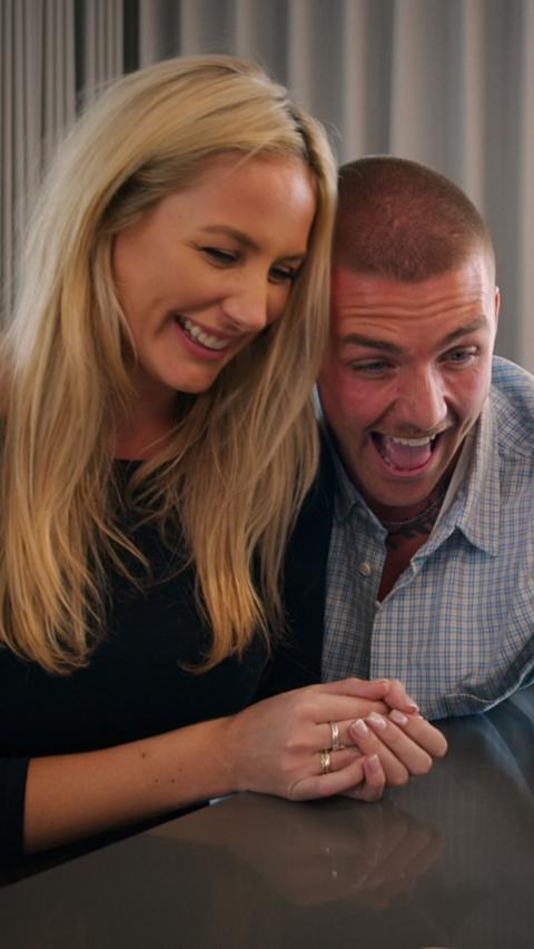 A woman with long blonde hair and a man with short hair smiling