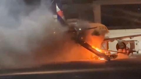 Plane surrounded by fire and smoke on an airport tarmac