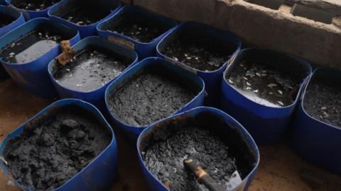 Black buckets filled with dark mud-like substance