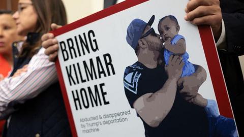 A person holds a sign with a picture of Kilmar Ábrego García