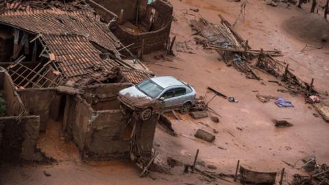 An aerial view shows a partly destroyed house, with a car balancing on the roof, after a dam burst in the village of Bento Rodrigues, in Mariana, Brazil on 6 November 2015.