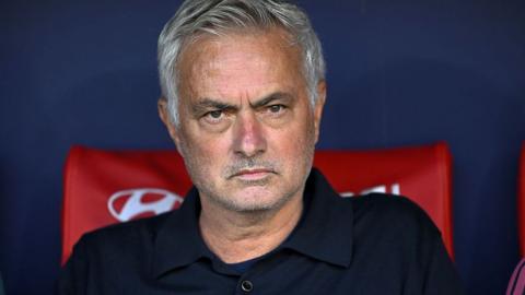 Jose Mourinho sat in the dugout with a stern expression

