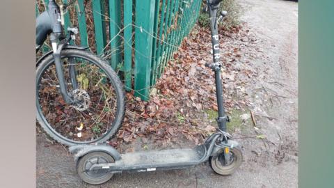 The modified scooter photographed parked on a muddy lane