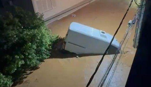 A partly submerged van is dragged along a street by yellow mudwaters.