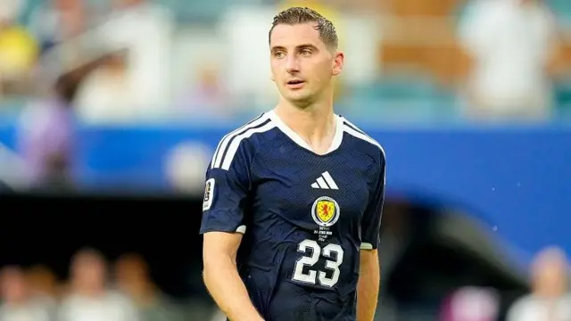 Kenny McLean in a dark blue Scotland shirt watches on during their World Cup match against Brazil
