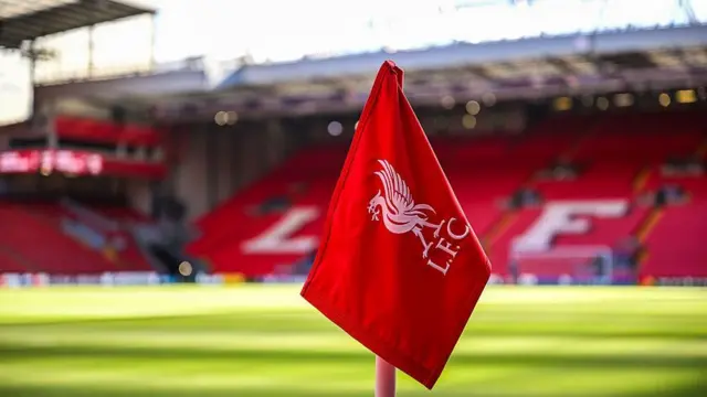 A close-up image of a corner flag at Anfield. The empty Kop is out of focus in the backgorund.