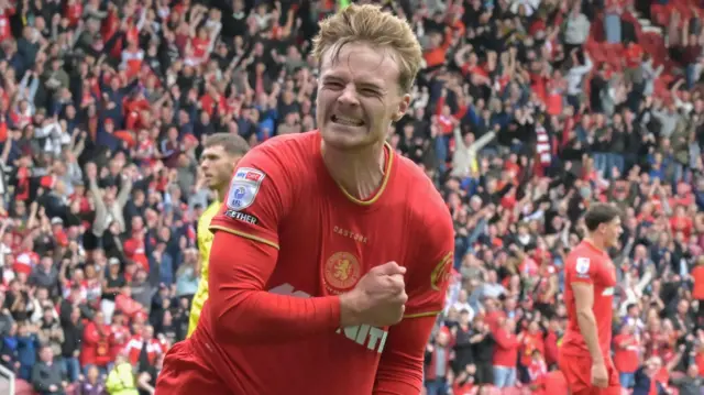 Tommy Conway, wearing Middlesbrough's red home kit, pumps his fist as he runs and celebrates a goal against Norwich City