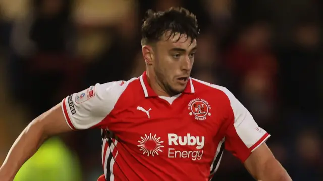 Harrison Holgate, with his arms outstretched and the ball at his feet, playing for Fleetwood last season 