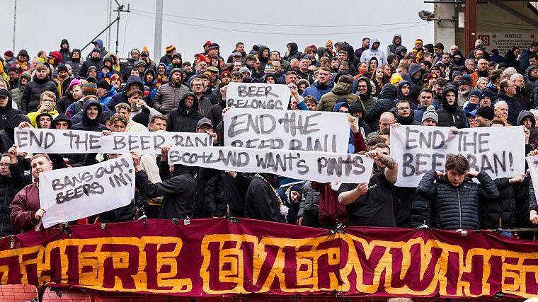 Motherwell fans hold signs protesting the alcohol ban at Scottish football grounds