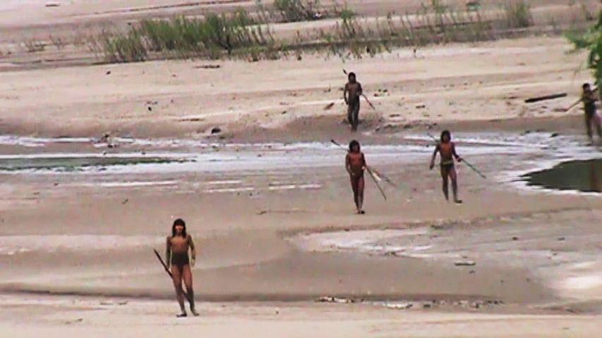 Mashco Piro people approach the Nomole control post  across a mostly dry river bed