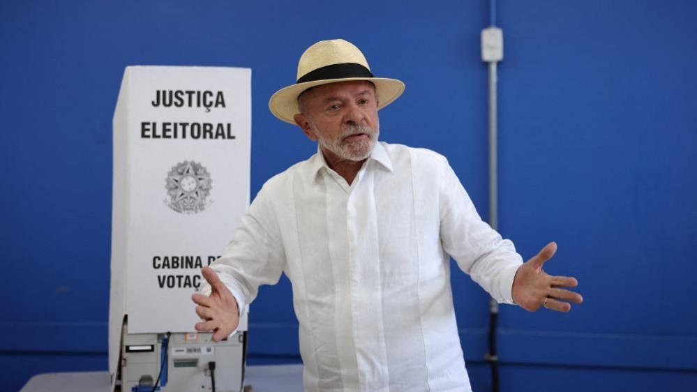Luiz Inácio Lula da Silva stands beside a voting booth marked “Justiça Eleitoral” after casting a ballot in Brazil’s general election in São Bernardo do Campo