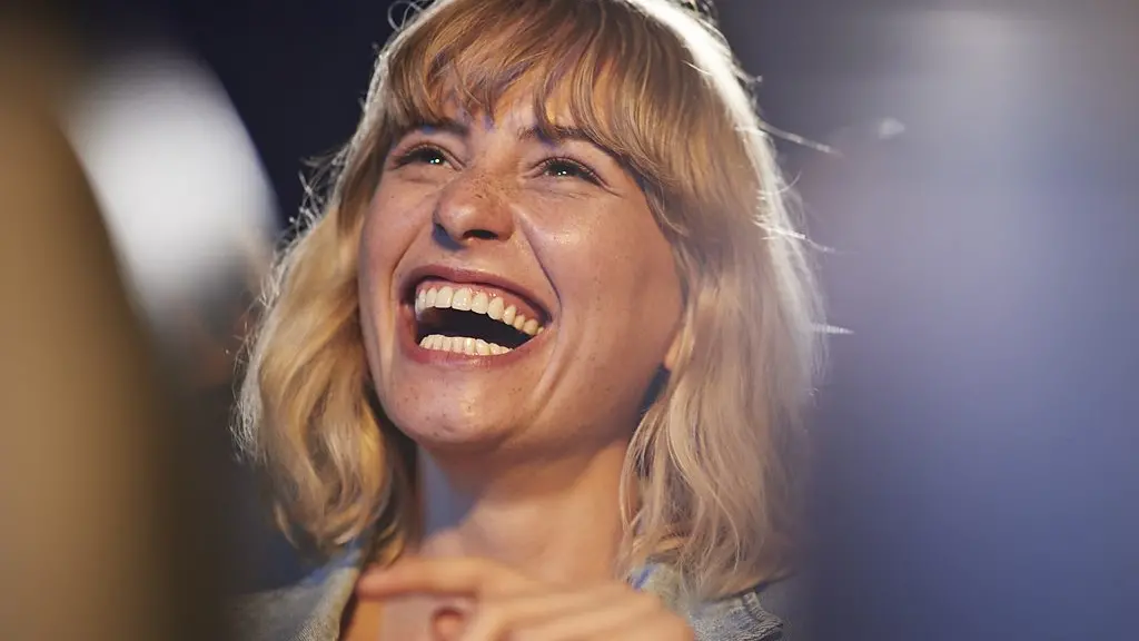 A woman with shoulder-length, blonde hair laughs while dressed in a light blue denim jacket (Credit: Getty Images)