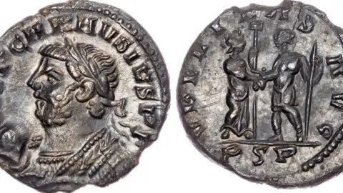 Both sides of a very misshapen and chipped silver Roman coin laid against a white background. One side features an emperor and the other features two Roman figures shaking hands.