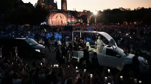 Pope Leo on his mobile travelling through huge crowds in Lourdes