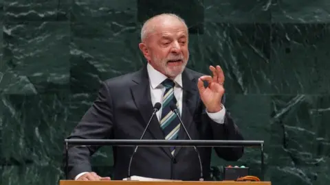 Olga Fedorova/EPA/Shutterstock Brazilian President Luíz Inácio Lula da Silva speaks during the General Debate of the 81st session of the United Nations General Assembly in New York on 22 September 2026. He is wearing a dark suit, a striped tie and a white shirt and is gesturing while he is speaking. 