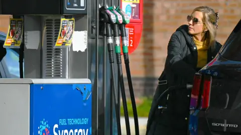 A woman fills up her car with petrol 