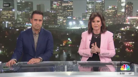 Man in navy suit and woman in pink blazer presenting news programme