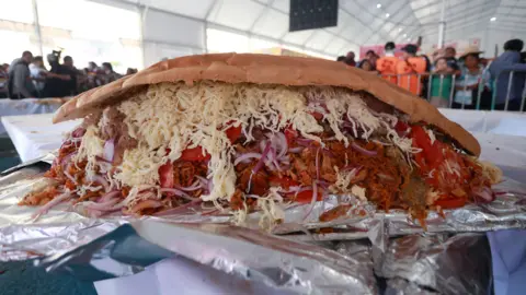 A massive sandwich full of cheese, onions, meet and peppers. 