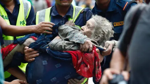 Rescuers transport an elderly woman rescued from flooded area