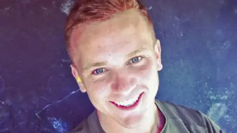 A selfie-style image of a man wearing a green T-shirt and smiling while looking into the camera. 