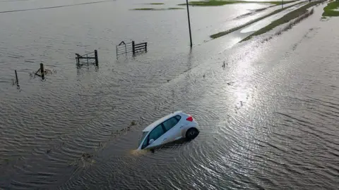 Car on its side lying in waterlogged field