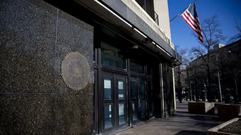 Close-up of the entrance of the FBI headquarters, with the US flag flying above it, in Washington DC