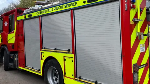 The side of a fire engine with Cheshire Fire & Rescue Service emblazoned across a luminous yellow panel