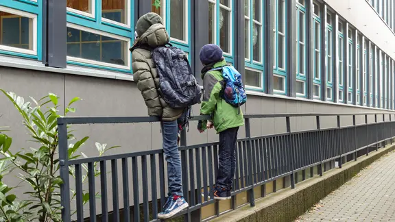 Schüler beobachten vor einem Hamurger Gymnasium ihre Klassenkameraden durch das Fenster. Da Klassenarbeiten in allen Jahrgängen, in denen es um einen Abschluss oder eine Versetzung geht, geschrieben werden, sind einige Schüler in kleinen Gruppen doch in der Schule. Wegen des Corona-Virus bleiben in der Hansestadt alle Schulen und Kitas geschlossen. (Foto vom 16.12.2020)