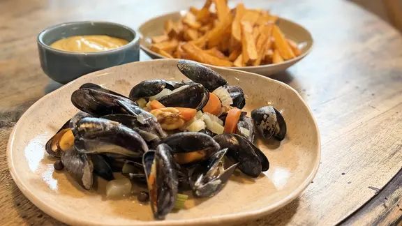 Miesmuscheln und Pommes frites auf Tellern mit Mayonnaise in einem Schälchen