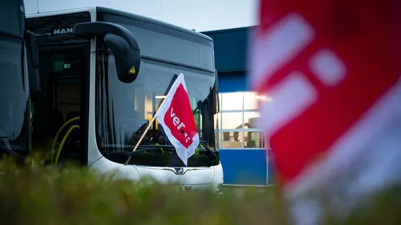 Eine verdi-Fahne hängt an einem geparkten Linienbus auf dem Betriebshof der Autokraft GmbH.