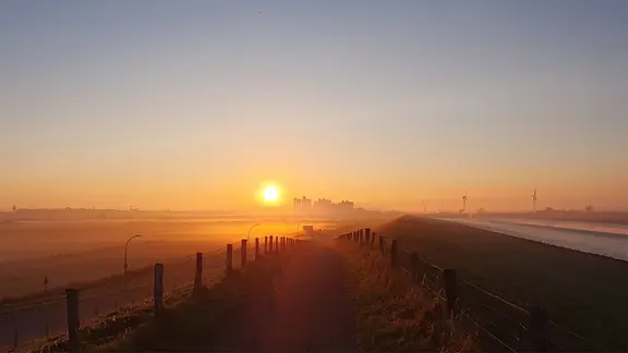 Ein Deich bei Sonnenuntergang.