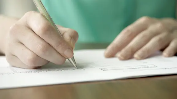 Eine weibliche Hand schreibt Tagebuch.