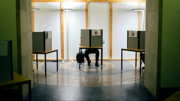 Ein Mann sitzt in einer kleinen Wahlkabine.