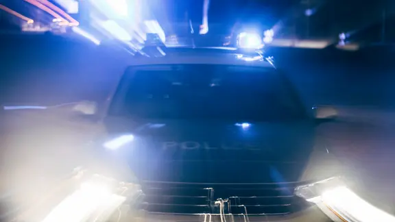 Streifenwagen fährt bei Nacht