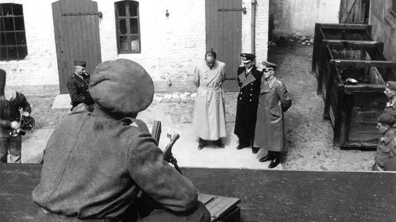 Die drei Gefangenen Albert Speer, Karl Dönitz und Alfred Jodl werden von britischen Soldaten bewacht.