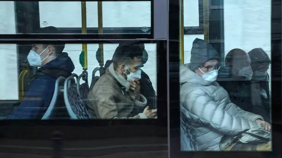 Fahrgäste in einem Bus tragen FFP2-Masken.