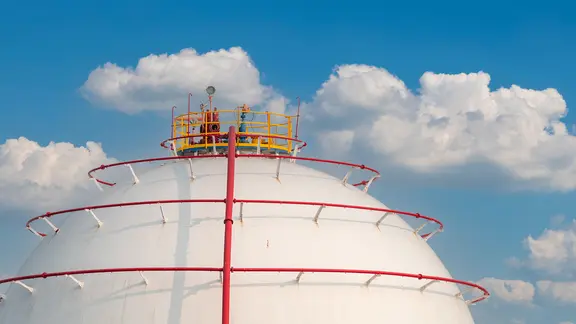Gasspeicher vor blauem Himmel mit weißen Wolken.
