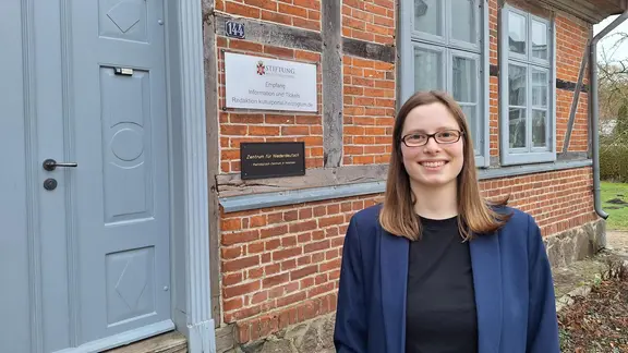 Die neue Leiterin des Zentrums für Niederdeutsch in Holstein, Marie Sophie Koop, steht vor der Eingangstür des Zentrums.