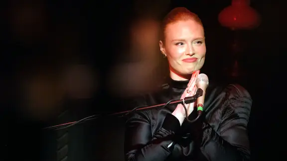 Sängerin Freya Ridings sitzt vor einem Mikrofon und faltet die Hände.