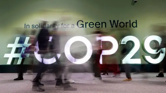 Menschen gehen durch das Konferenzgebäude, in dem der UN-Klimagipfel COP29 in Baku stattfindet.